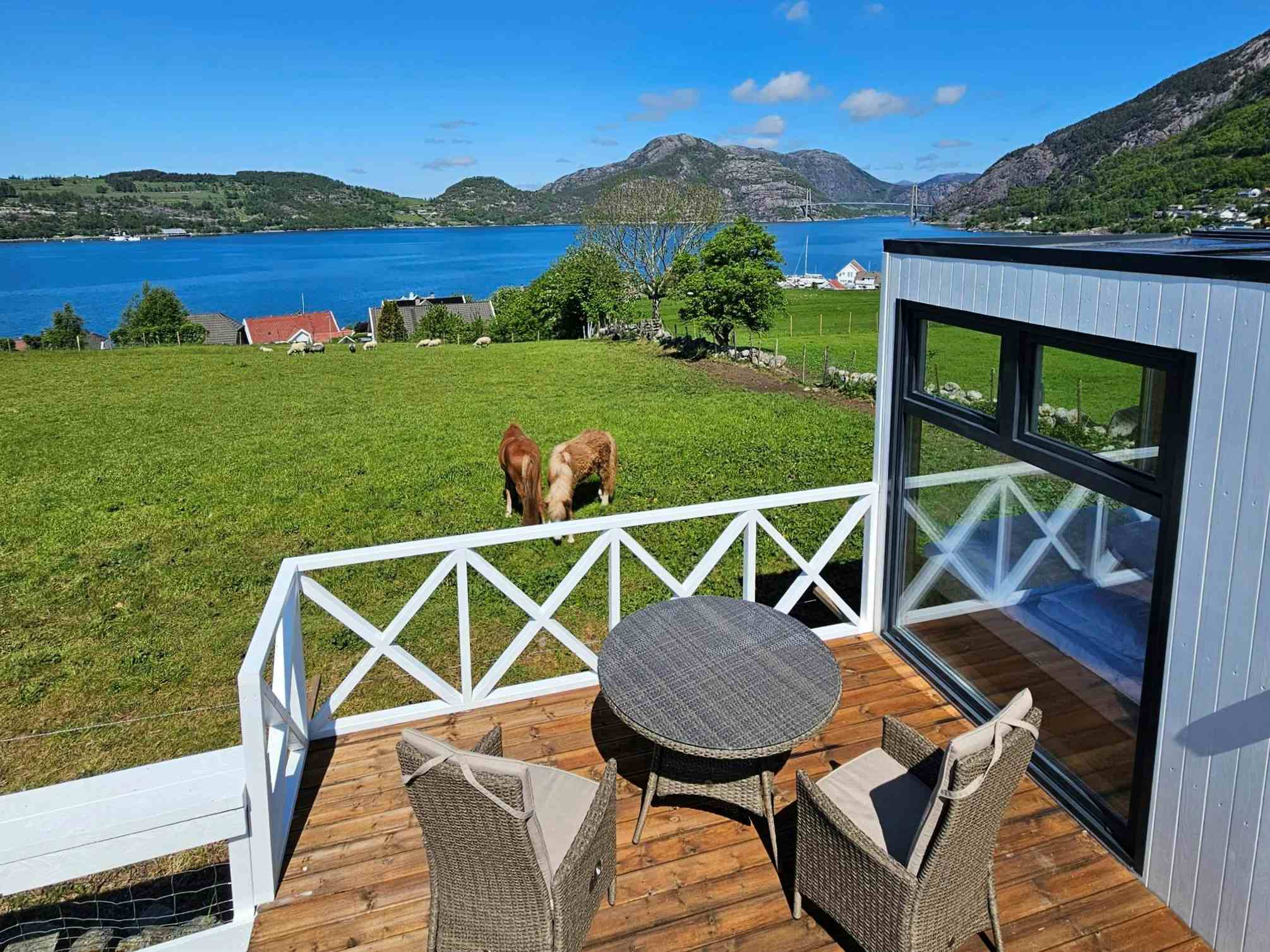Fjordutsikt og hester fra minihyttene på Gøysa Gard.